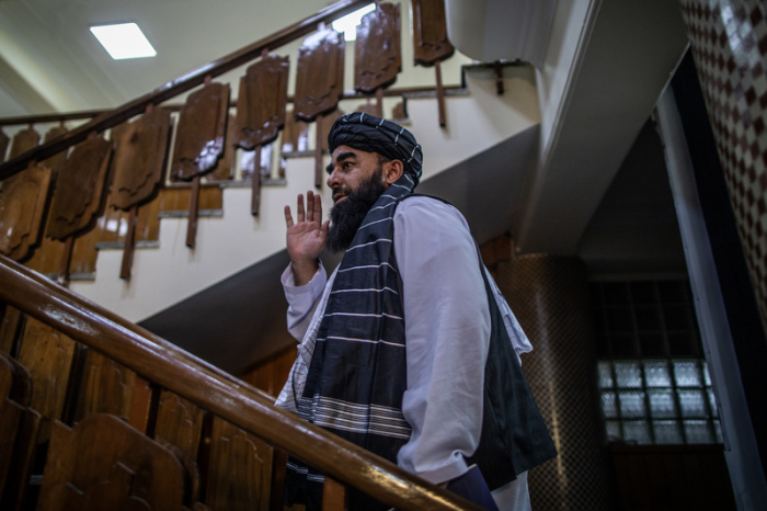 Zabihullah Mudschahid, Sprecher der militant-islamistischen Taliban-Regierung, winkt, als er nach einer Pressekonferenz in Kabul die Räumlichkeiten verlässt. Foto: Oliver Weiken/dpa