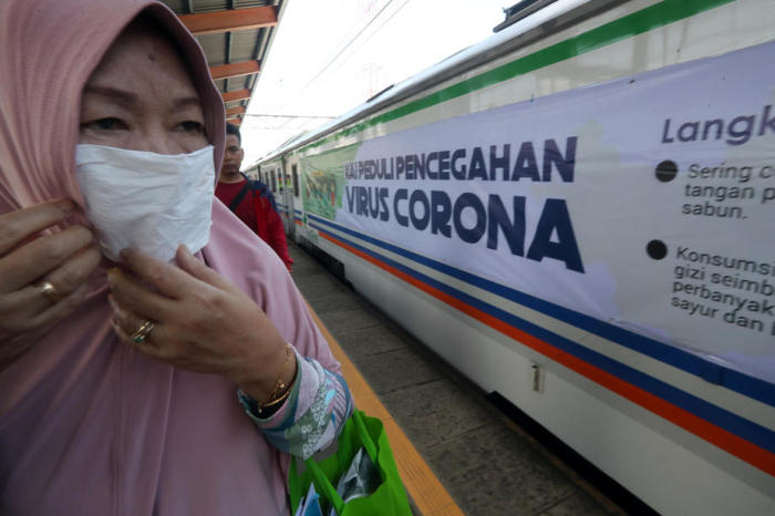 Eine Passagierin der indonesischen Pendlerlinie trägt eine Maske am Bahnhof Depok, West-Java. Foto: epa/Bagus Indahono