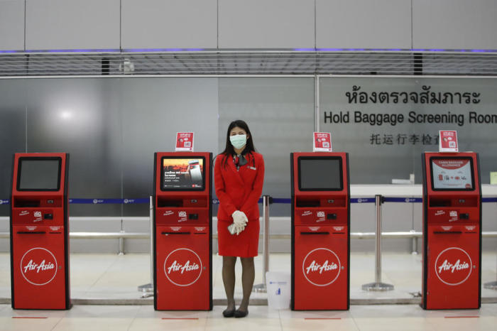 Eine Mitarbeiterin des Bodenpersonals von Thai AirAsia wartet vor den Self-Check-in-Schaltern in der Abflughalle des Bangkoker Don Mueang Airport auf Fluggäste. Bisher ist die Zahl der Passagiere jedoch noch recht überschaubar. Foto: epa/Diego Azubel
