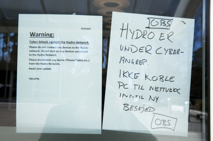 An einem Verwaltungsgebäude des norwegischen Aluminiumkonzerns Norsk Hydro hängen Zettel, die auf einen Cyberangriff gegen das Unternehmen hinweisen. Foto: Pedersen, Terje/Ntb Scanpix/dpa