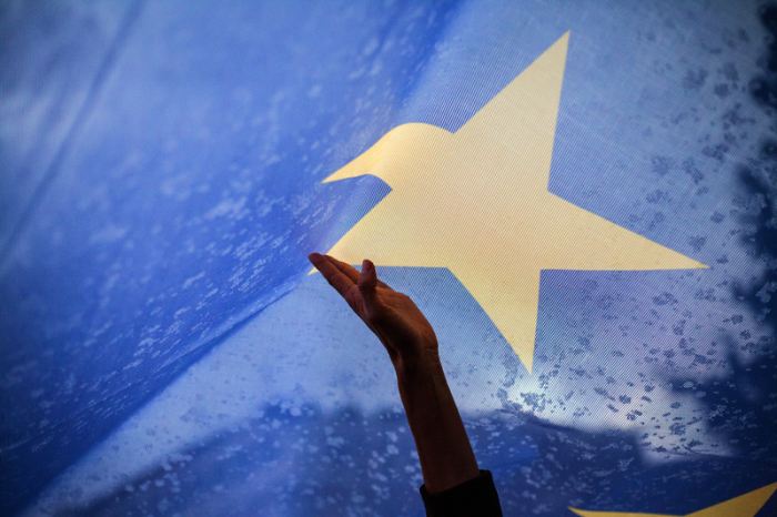 Eine Hand greift nach einem Stern auf einer EU-Flagge während einer Demonstration vor dem Parlament. Foto: Socrates Baltagiannis/Dpa