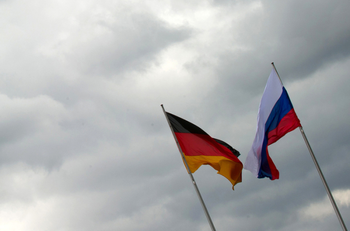 Die russische und die deutsche Flagge wehen vor dem Bundeskanzleramt vor einem grauen Himmel. Foto: picture alliance/dpa