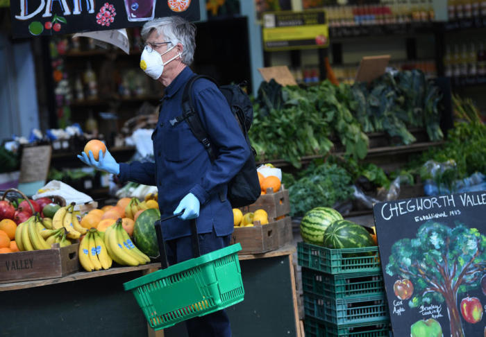 Ein Maskierter kauft auf dem Borough Market in London Orangen ein. Foto: epa/Neil Hall