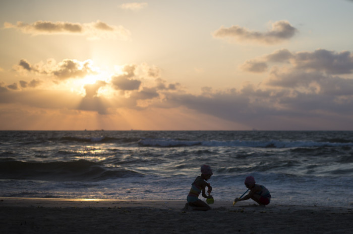 Zwei Mädchen spielen im Sand, während die Sonne über dem Mittelmeer untergeht. Archiv Foto: epa/Mohamed Hossam