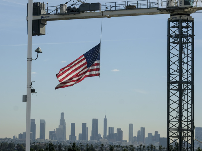 Eine US-Flagge hängt an einem Kran auf einer Baustelle in Hollywood. Im Hintergrund ist die Skyline von Los Angeles zu sehen. Foto: Ringo Chiu/Zuma Wire/dpa