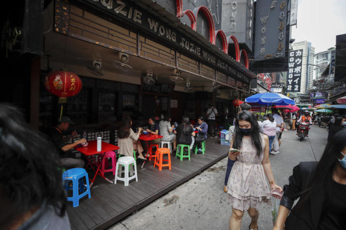 Leute essen zu Mittag vor einer geschlossenen A-Go-Go-Bar in Bangkok. Foto: epa/Diego Azubel