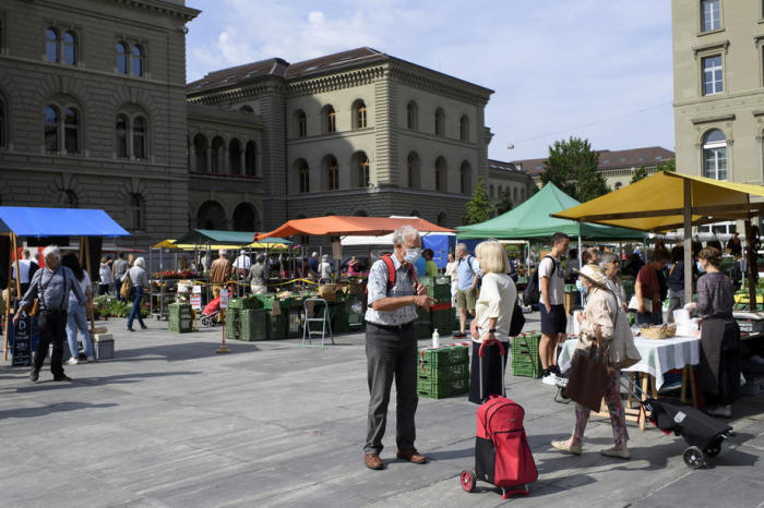 Die Kunden, die eine schützende Gesichtsmaske tragen, besuchen den wöchentlichen Lebensmittelmarkt in Bern. Foto: epa/Anthony Anhang
