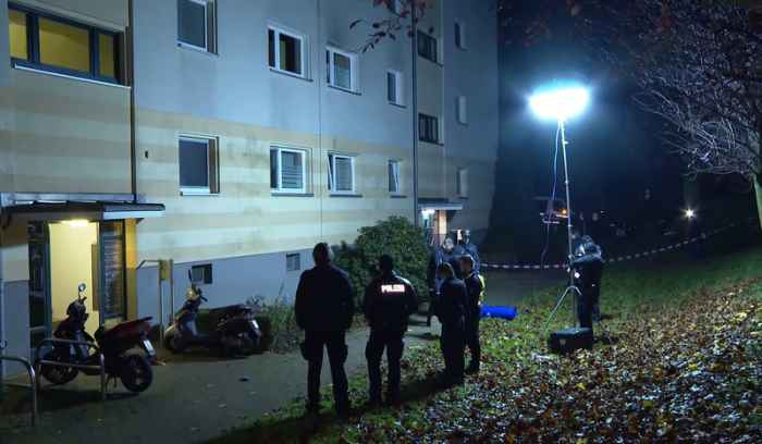 Polizisten stehen vor einem Wohnhaus. Ein Unbekannter hat in der Nacht eine Frauenleiche an der Straße eines Wohngebiets abgelegt. Foto: TeleNewsNetwork/Dpa