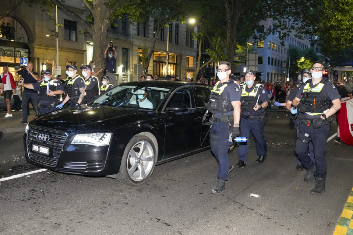 Die Polizei räumt Fans des serbischen Tennisspielers Novak Djokovic aus dem Weg, als ein Auto die Büros seiner Anwälte verlässt. Foto: Mark Baker/Ap/dpa