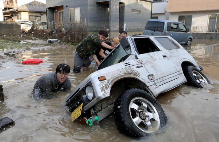 Anwohner versuchen, ein untergetauchtes Auto zu retten, nachdem schwere Regenfälle eine Überschwemmung verursacht haben. Foto: epa/Jiji-presse