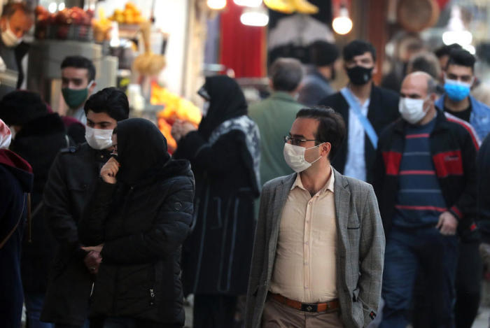 Leute mit Gesichtsmasken laufen über einen Straßenmarkt in Teheran. Foto: epa/Babedin Taherkenareh