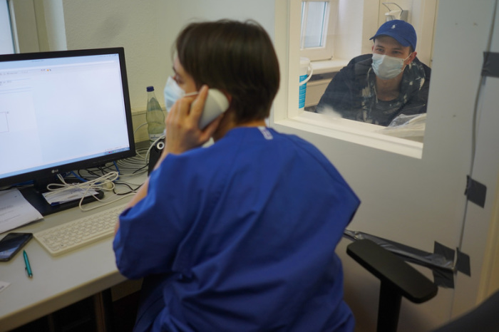 Eine Ärztin befragt über eine Sprechanlage einen Patienten zu seinen Symptomen. In Berlin sind bisher mindestens 48.771 Labortests auf das neue Coronavirus durchgeführt worden. Foto: Jörg Carstensen/dpa