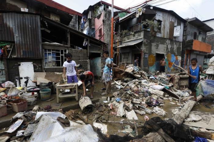 Einwohner kehren zurück, um schlammiges Hab und Gut aus ihren Häusern in einer von der Flut betroffenen Gemeinde in der Stadt Marikina zu bergen. Foto: epa/Rolex Dela Pena