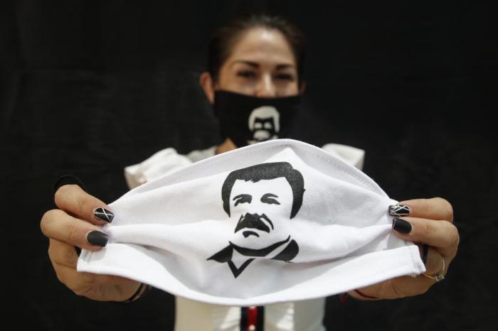 Eine Frau hält eine Gesichtsmaske, die den berühmten Drogenboss Joaquin 
