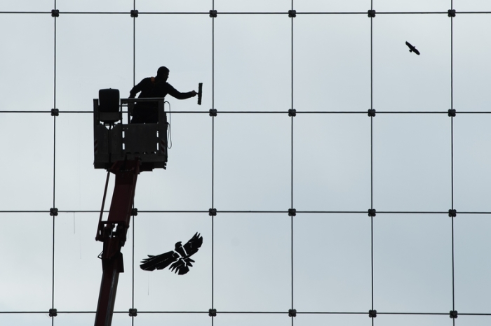 Ein Gebäudereiniger ist als Silhouette zu sehen, während er die gläserne Fassade des World Trade Center (WTC) putzt. Rund fünf Jahre nach Einführung des Mindestlohns bekommen Arbeitnehmer und die Wir... Foto: Sebastian Kahnert/dpa-zentralbild/dpa
