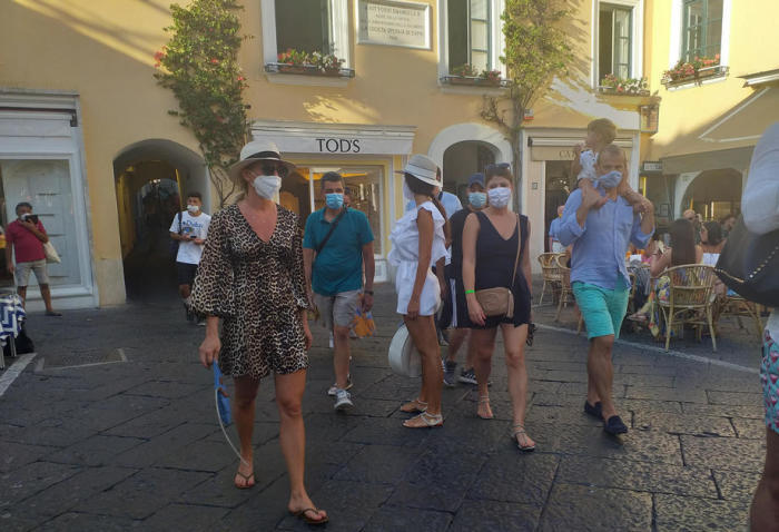 Auf dem zentralen Platz von Capri gehen Menschen mit schützenden Gesichtsmasken. Foto: epa/Giuseppe Catuogno