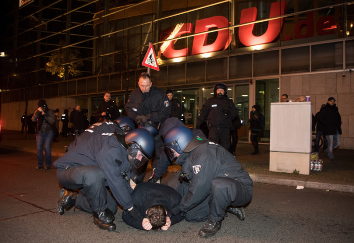 Die Berliner Polizei nimmt einen Demonstranten vor der CDU-Bundeszentrale fest. Foto: epa/BERND VON JUTRCZENKA