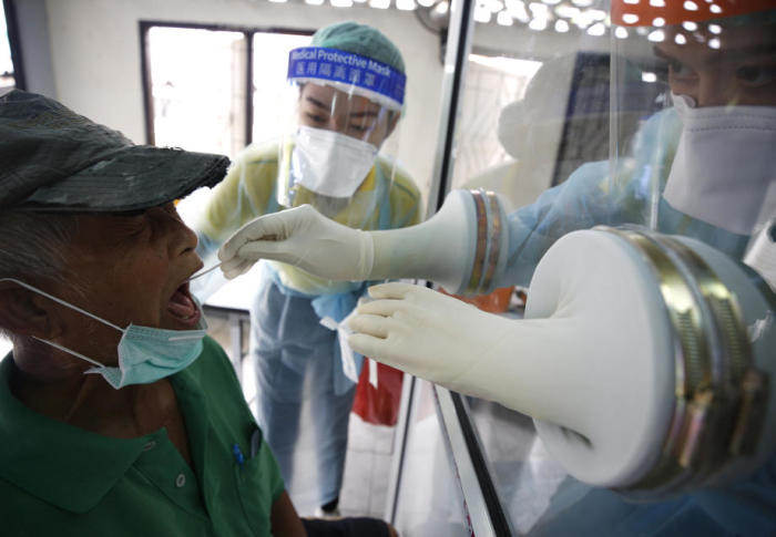 Medizinische Personal entnimmt eine Speichelprobe aus dem Rachen eines Patienten, um sie auf SARS-CoV-2 zu testen. Foto: epa/Narong Sangnak