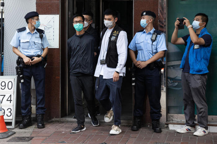 Polizeibeamte der Abteilung für nationale Sicherheit eskortieren Leung Kam-wai (2L), ein Mitglied der Hongkonger Allianz zur Unterstützung der patriotischen demokratischen Bewegungen Chinas. Foto: epa/Jerome Favre