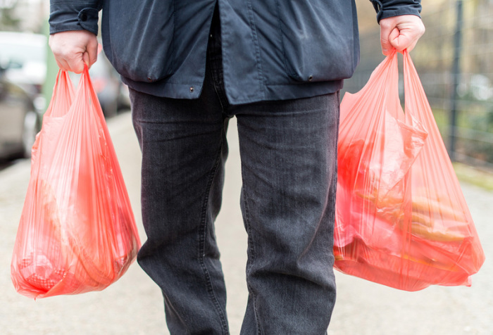 Ein Mann trägt seine Einkäufe in Plastiktüten nach Hause. Bundesumweltministerin Svenja Schulze will ein Verbot von Plastiktüten in Angriff nehmen. Foto: Sebastian Gollnow/Dpa