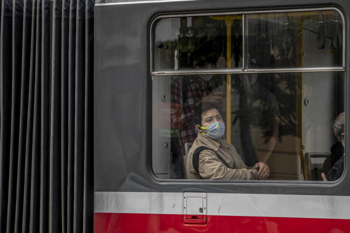 Ein Mann mit einer schützenden Gesichtsmaske sitzt in einer Straßenbahn in Prag. Foto: epa/Martin Divisek