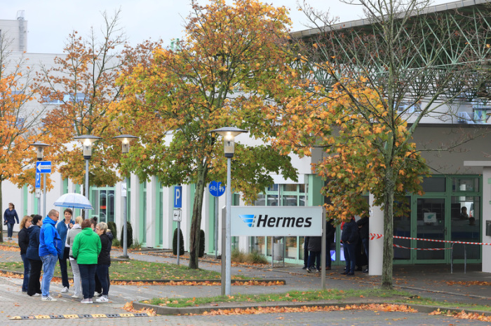 Mitarbeiter stehen vor dem Haupteingang des Paketdienstleisters Hermes. Foto: Peter Gercke/Dpa-zentralbild/dpa