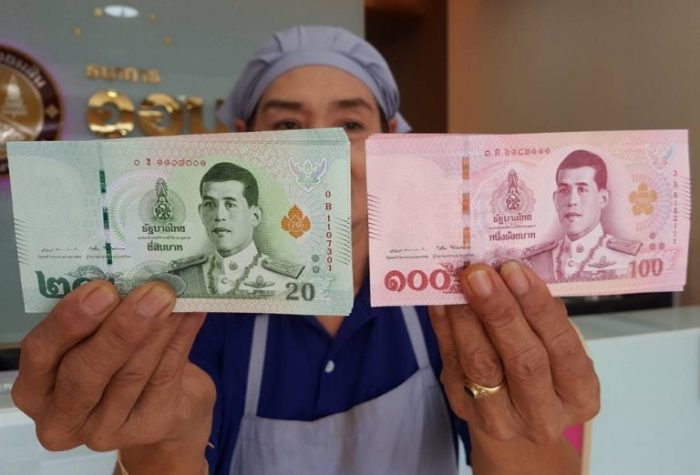 Eine Verkäuferin hält neue Banknoten in den Händen. Foto: Khaosod
