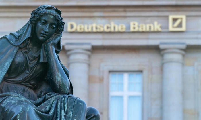 Eine Figur des Gutenberg-Denkmals ist vor einer Filiale der Deutschen Bank in Frankfurt am Main abgebildet. Foto: epa/Thorsten Wagner