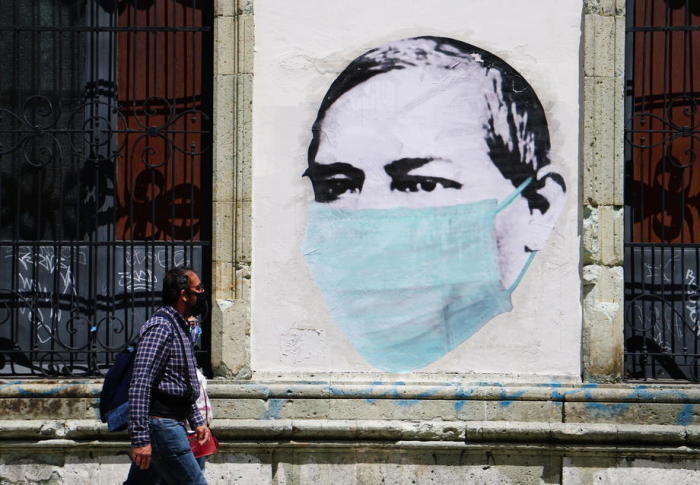 Ein Paar geht in Oaxaca neben einem Wandbild spazieren, das auf die Verwendung der Gesichtsmaske anspielt. Foto: epa/Daniel Ricardez