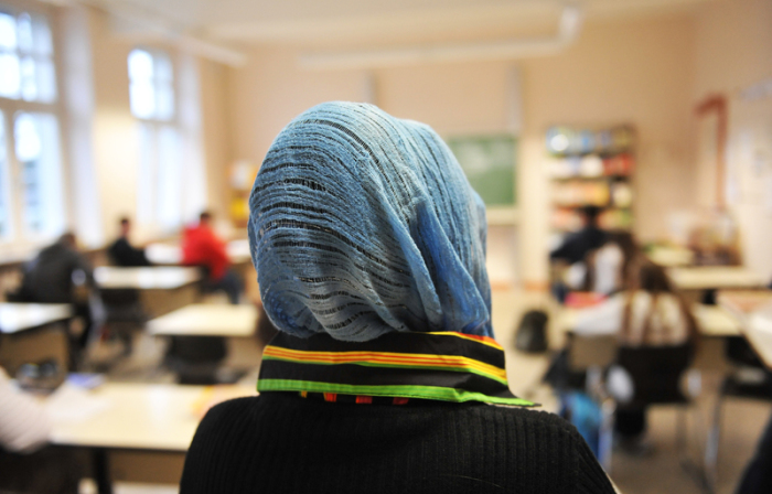 Eine türkische Schülerin mit Kopftuch nimmt am Unterricht in einer Schule teil. Foto: Bernd Thissen/Dpa