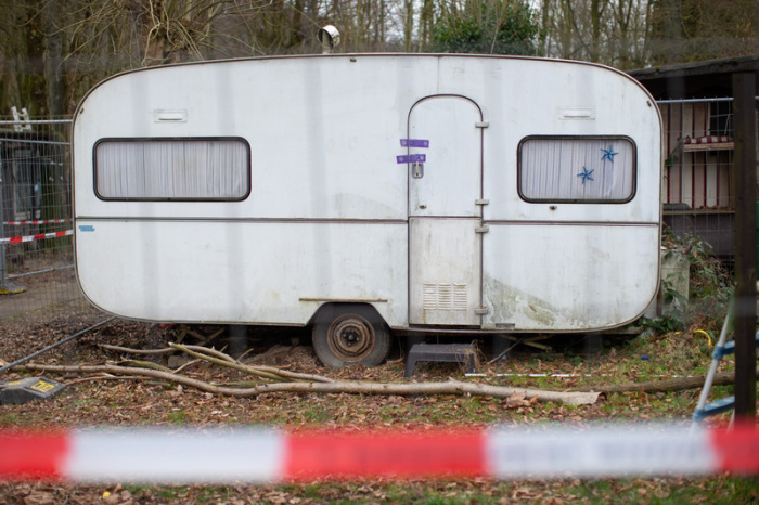 Hinter einem Zaun und Polizeiabsperrband steht ein Wohnwagenanhänger auf dem Campingplatz Eichwald. Foto: Friso Gentsch/Dpa