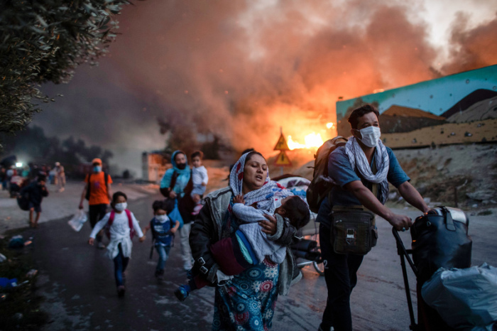 Migranten fliehen vor einem erneuten Feuers mit ihren Habseligkeiten aus dem Flüchtlingslager Moria, nachdem zuvor bereits mehrere Feuer das Lager nahezu vollständig zerstört haben. Foto: Petros Giannakouris/dpa