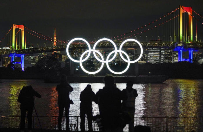 Das Denkmal der olympischen Ringe ist beleuchtet, während Fotografen Fotos von den beleuchteten Ringen am Ufer des Odaiba Marine Parks in Tokio machen. Foto: epa/Kimimasa Mayama