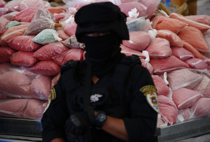 Schwer bewaffnetes Sicherheitspersonal bewacht auf einer Pressekonferenz beschlagnahmtes Rauschgift. Foto: epa/Narong Sangnak