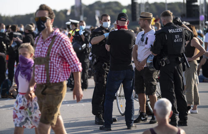 Polizeibeamte sprechen mit einem Demonstranten der Münchner Theresienwiese der Maskenpflicht nicht nachkommt. Foto: epa/Lukas Barth-tuttas