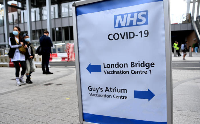 Leute gehen an einem Covid-Impfschild vor einem Krankenhaus im Zentrum Londons vorbei. Foto: epa/Andy Rain
