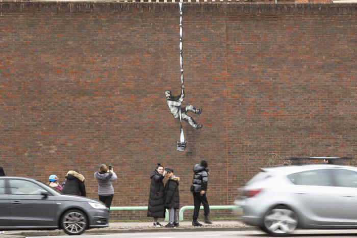 Leute fotografieren das neue Banksy-Kunstwerk, das an einer Seitenwand eines stillgelegten Gefängnisses in Reading angebracht wurde. Foto: epa/Joshua Bratt