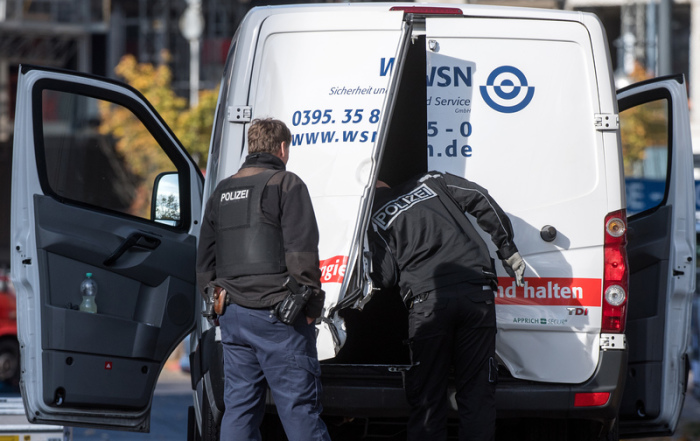 Polizeibeamte stehen an einem Geldtransporter mit aufgebrochenen Türen. Foto: Bernd von Jutrczenka/Dpa