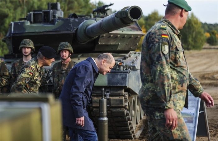Bundeskanzler Olaf Scholz fährt unter dem Geschützrohr eines Leopard 2 hindurch. Foto: epa/Friedemann Vogel