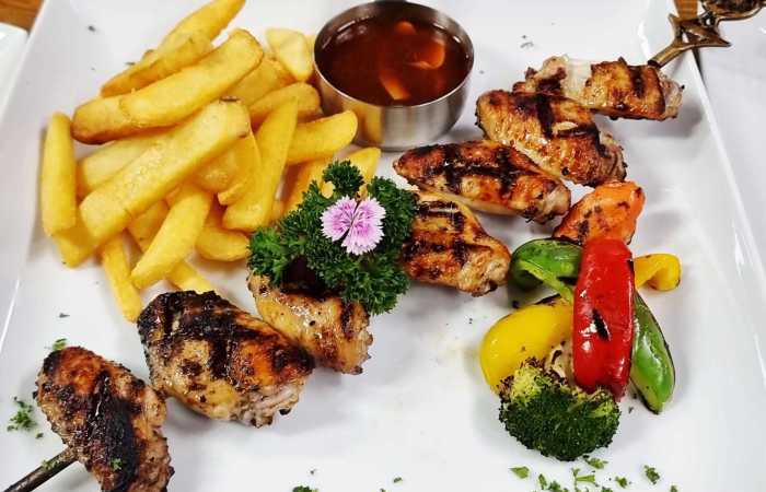 Gegrillte Chicken-Wings am Spieß mit Barbecuesauce, knusprigen Pommes Frites und buntem Grillgemüse. Fotos: Jaybee'Swiss Restaurant