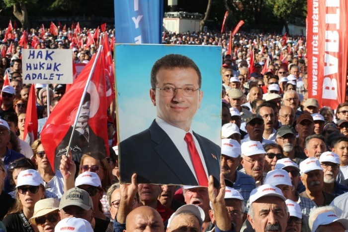 Eine Person hält ein Foto des ehemaligen Istanbuler Bürgermeisters Ekrem Imamoglu in den Händen, während Anhänger der Republikanischen Volkspartei (CHP) der Türkei daneben stehen. Foto: epa/Necati Savas