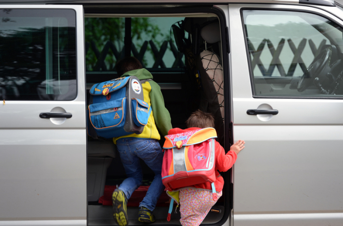 Schulkinder steigen in ein privates Fahrzeug. Foto: Ralf Hirschberger/dpa-zentralbild/dpa