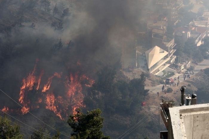 Ein Waldbrand brennt auf einem Hügel unweit von Wohnhäusern in einem Vorort von Athen. Eine Kombination aus heißem und trockenem Wetter mit starken Winden macht Griechenland jeden Sommer anfällig für Waldbrände. Foto: Yorgos Karahalis