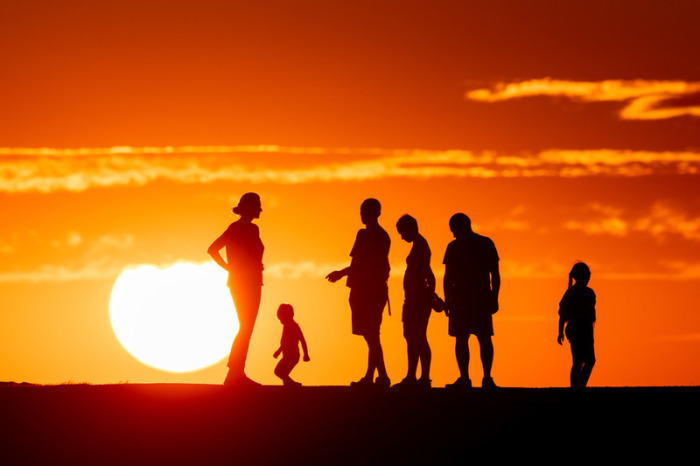 Menschen stehen auf der Halde Norddeutschland vor der untergehenden Sonne zusammen. Foto: Marcel Kusch/dpa
