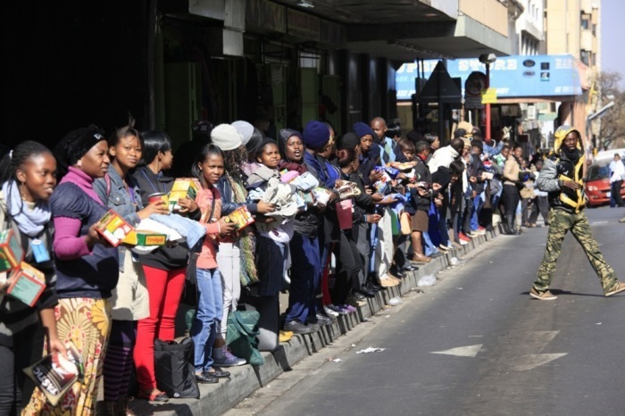 Einige der hunderten von Menschen bilden eine Menschenkette, um gespendete Lebensmittel und Kleidung zu einer nahe gelegenen Notunterkunft in der Innenstadt von Johannesburg zu bringen. Foto: epa/Kim Ludbrook