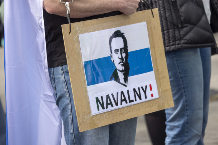 Ein Mann trägt ein Schild mit dem aufgedruckten Gesicht von dem gestorbenen Regimegegner Alexej Nawalny. Foto: Thomas Banneyer/dpa