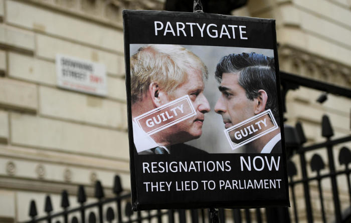 Ein Demonstrant hält ein Plakat des britischen Premierministers Boris Johnson und des Kanzlers Rishi Sunak vor der Downing Street in London hoch. Foto: epa/Andy Rain