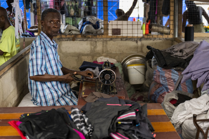Ein Mann arbeitet auf einem Markt an einem Bahnhof in Accra auf dem unter anderem Kleidung aus Europa verkauft oder weiterverarbeitet wird. Foto: Christophe Gateau/dpa