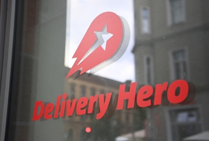 Logo und Schriftzug des Essenslieferdienstes Delivery Hero ist an einer Glasscheibe der Zentrale angebracht. Foto: Britta Pedersen/dpa-zentralbild/dpa