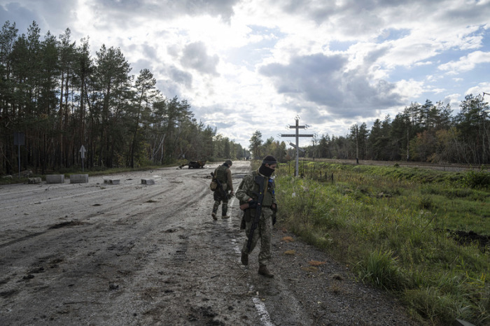 Ukrainische Soldaten gehen eine Straße entlang, während sie nach den Leichen ihrer Kameraden in der kürzlich zurückeroberten Stadt Lyman in der Ukraine suchen. Foto: Evgeniy Maloletka